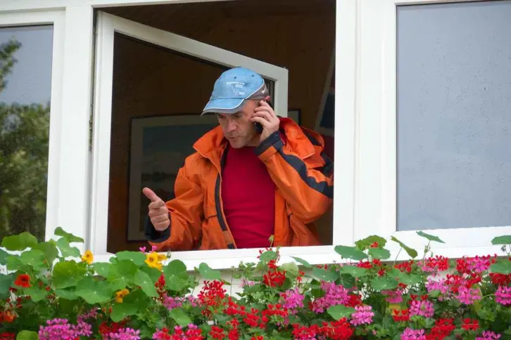 Ein Mann telefoniert am Fenster.