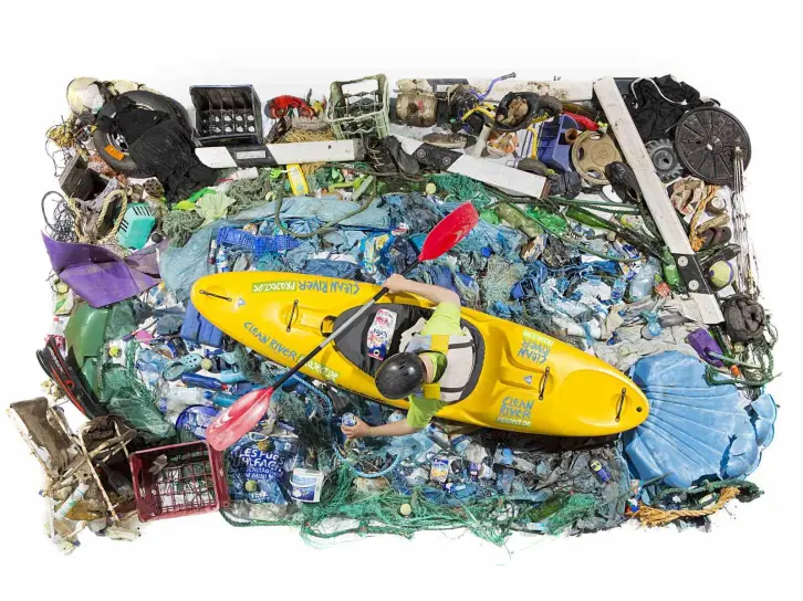 Ein Mann im Paddelboot von oben fotografiert, um ihn herum lauter Müll.