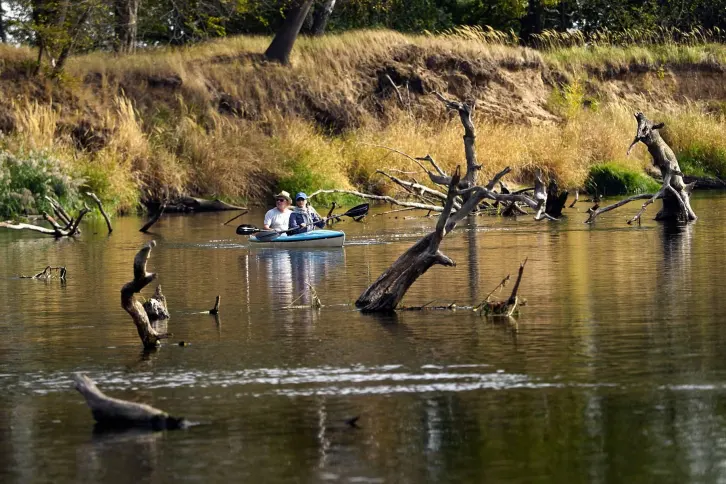Ein Paddelboot auf einem Fluss, indem tote B&auml;ume liegen.