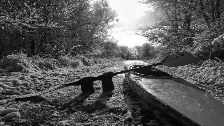 Ein Kajak mitten auf einem Waldweg in einer leicht verschneiten Landschaft