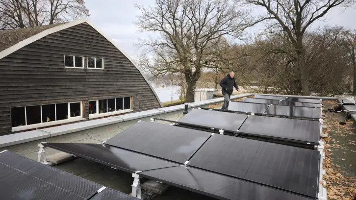 Soalrpanele auf einem Dach, im Hintergrund ein Fluss.